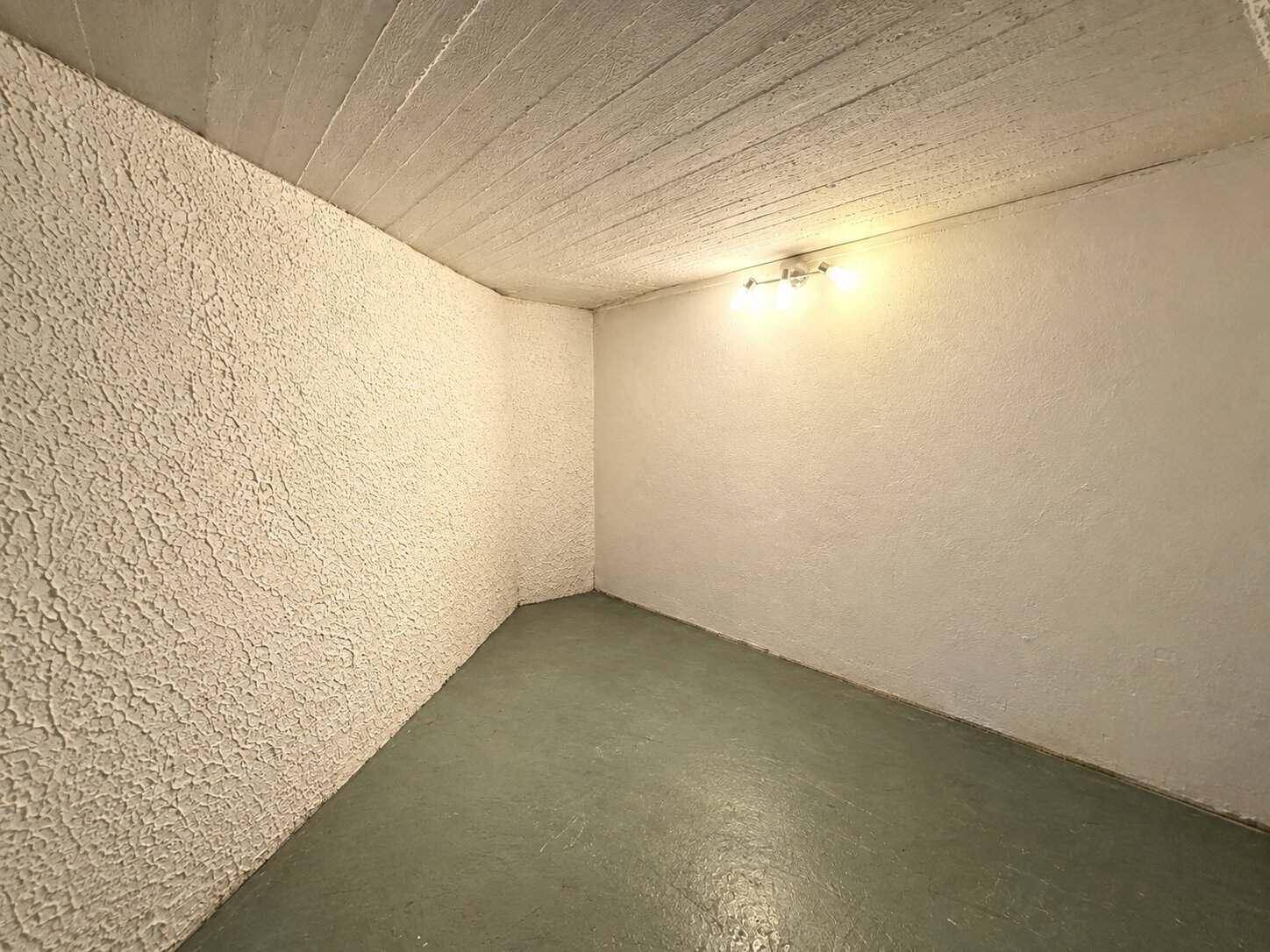 Einfacher Abstellraum oder Kellerraum mit strukturierten Wänden und robustem Betonboden.