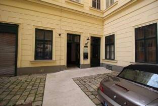 Eingangsbereich im historischen Innenhof mit Kopfsteinpflaster und einem geparkten Auto.