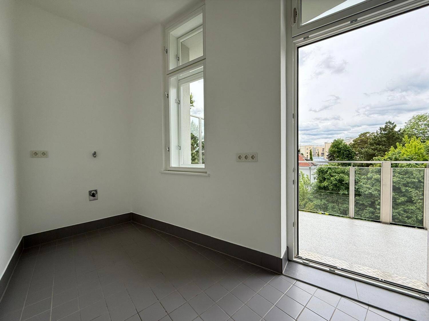 Praktischer Hauswirtschaftsraum mit Fliesenboden, Fenster und Zugang zum Balkon.