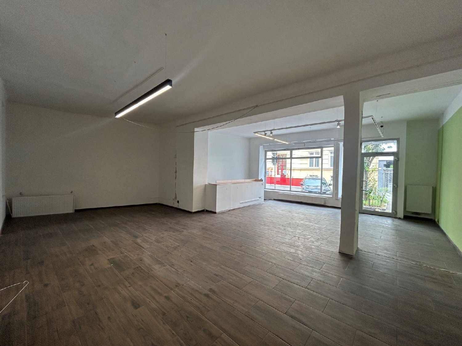 Heller Gewerberaum mit großen Schaufenstern zur Straße und dunklem Fliesenboden.