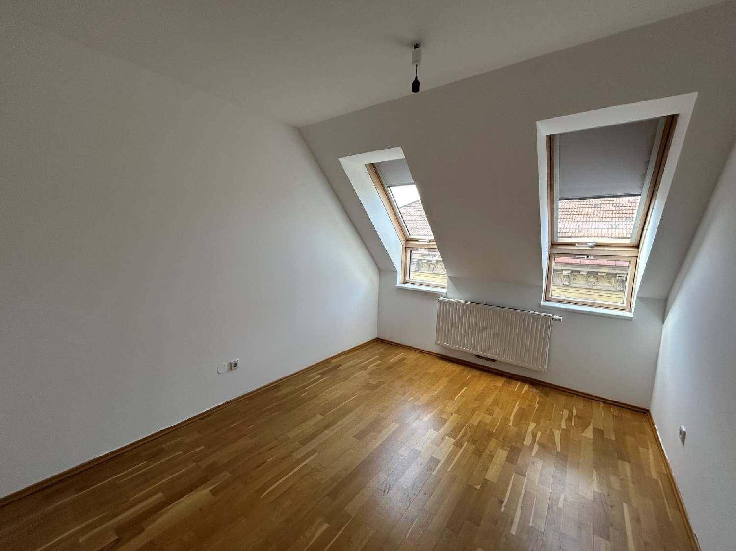 Schlafzimmer im Dachgeschoss mit Holzboden und zwei Dachfenstern, die viel Licht hereinlassen.