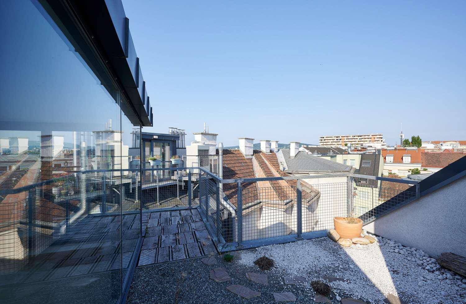 Dachterrasse mit Kiesbereich, Holzbelag und Panoramablick über die Stadt.