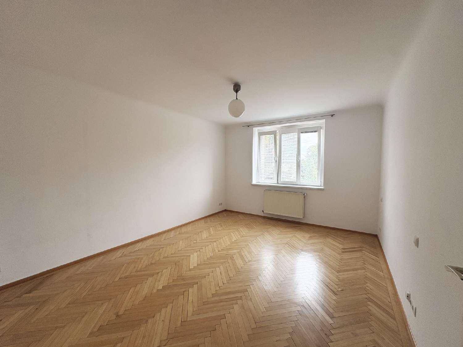 Leeres Schlafzimmer mit Fischgrätparkettboden und einem Fenster für natürliches Licht.