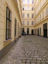 Langer Innenhof mit Kopfsteinpflaster und hohen Gebäudewänden, die eine geschützte Atmosphäre bieten.