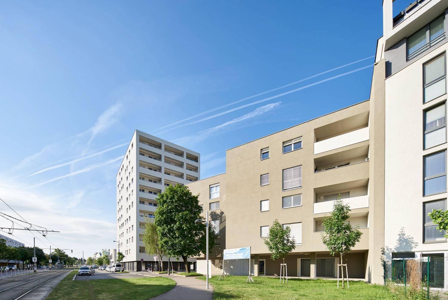 Moderne Wohngebäude mit klaren Linien, Balkonen und gepflegten Grünflächen an einem sonnigen Tag.