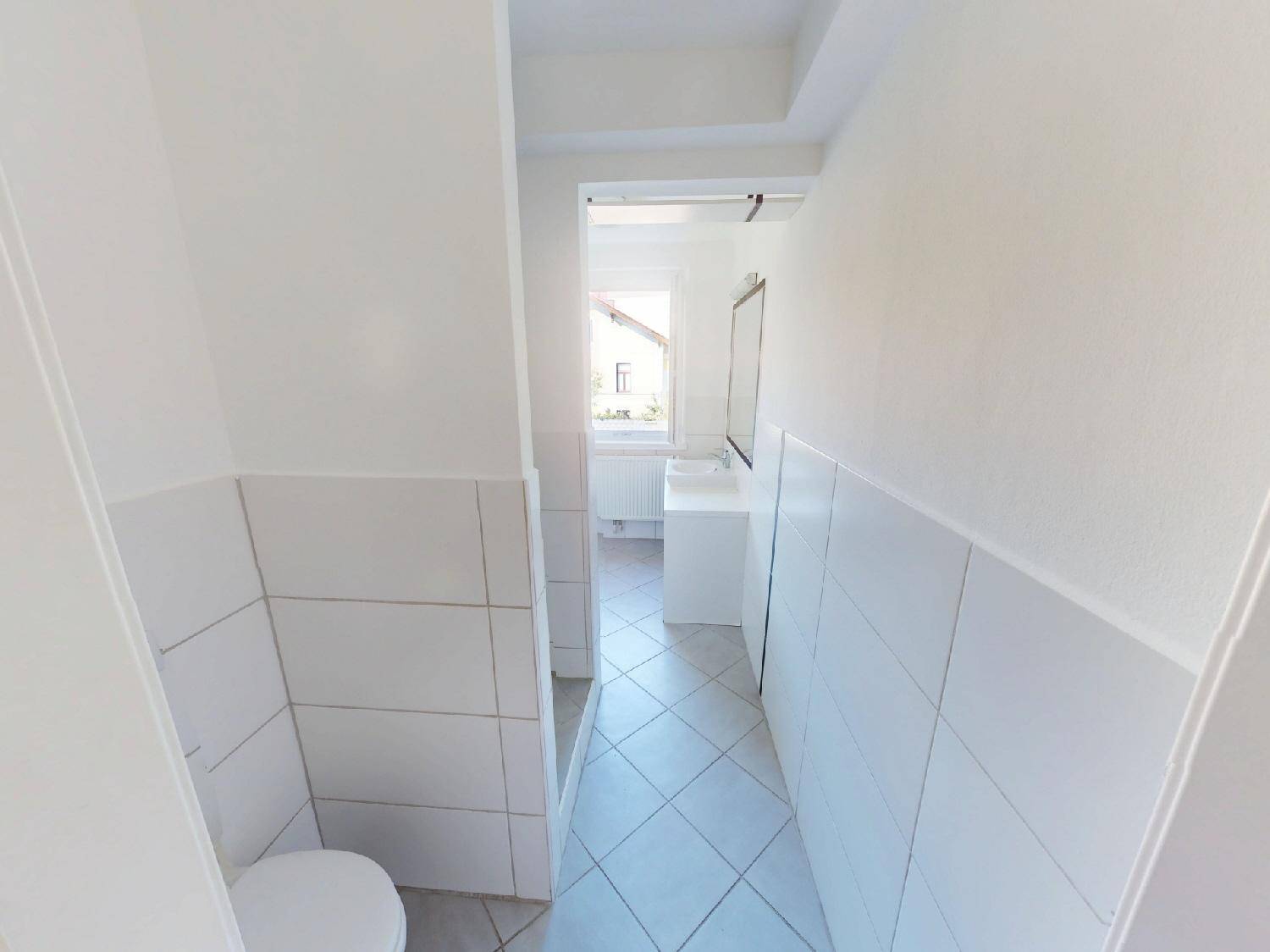 Helles Badezimmer mit WC, Waschbecken und Fliesenboden, gut beleuchtet.