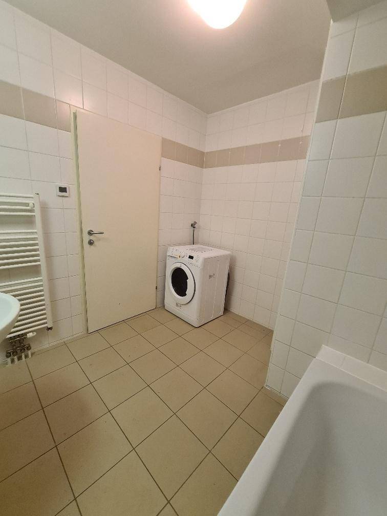 Badezimmer mit Fliesen, Badewanne, Waschbecken und einer praktischen Waschmaschine.