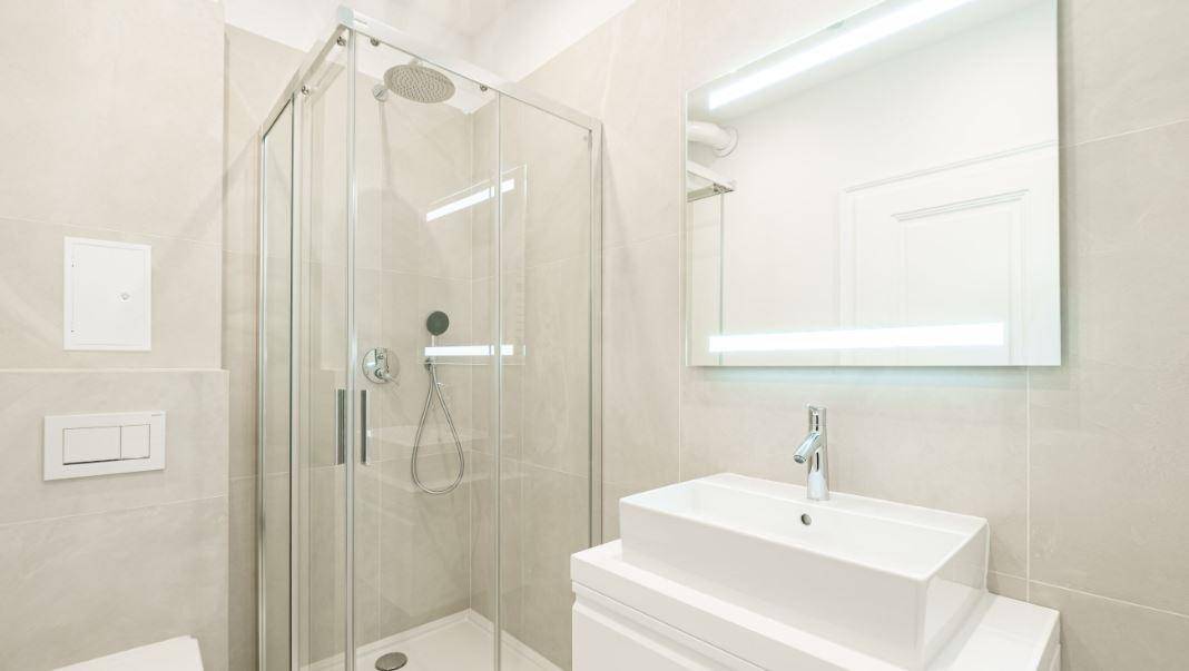 Modernes Badezimmer mit begehbarer Dusche, stilvollem Waschbecken und beleuchtetem Spiegel.