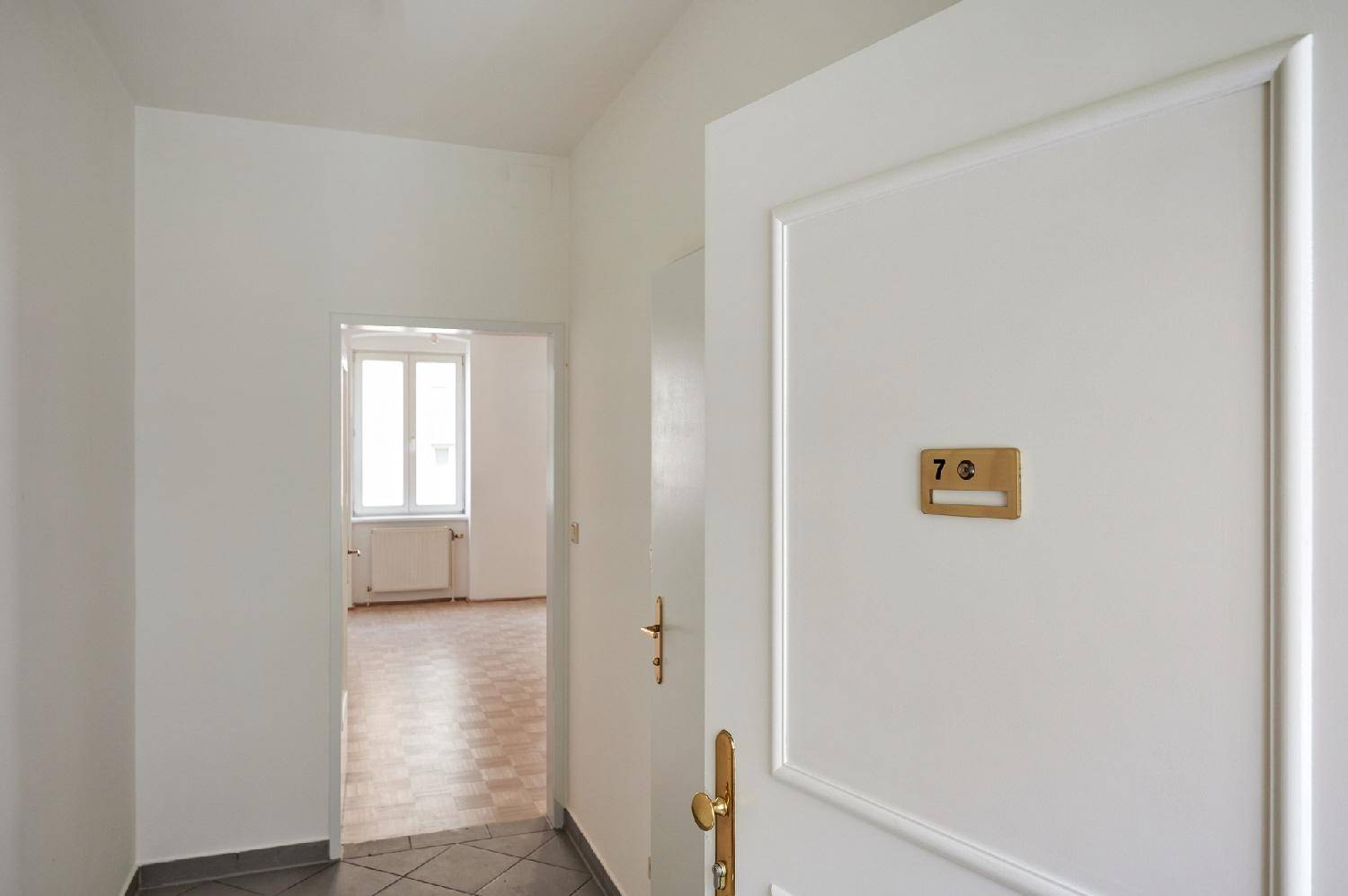 Heller Flur mit Eingangstür zur Wohnung 7B und Blick in den Wohnbereich.