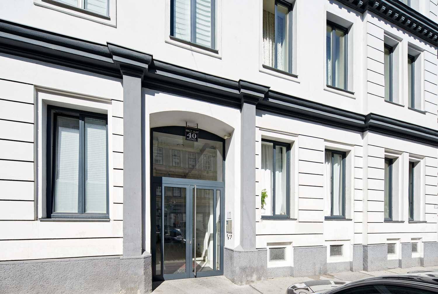 Eingangsbereich eines modernen Gebäudes mit großen Glastüren und klassischer Fassadengestaltung.