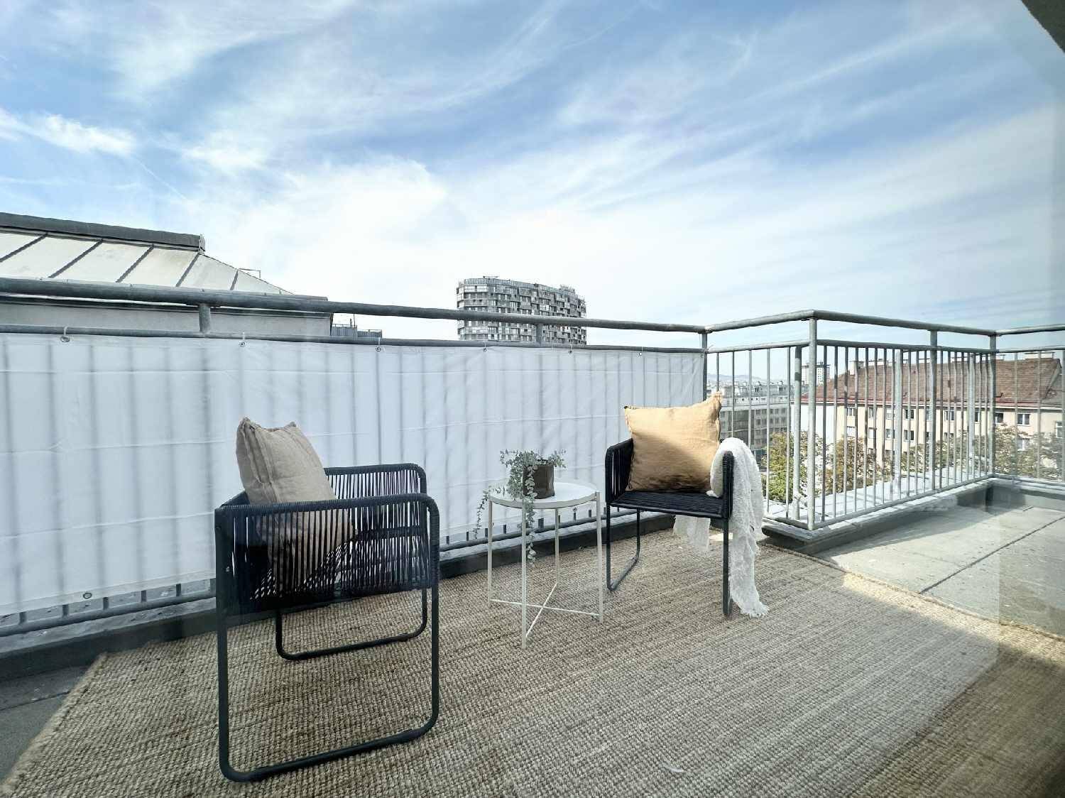 Geräumiger Balkon mit Outdoor-Sitzgelegenheiten und Blick auf die umliegende Stadtlandschaft.