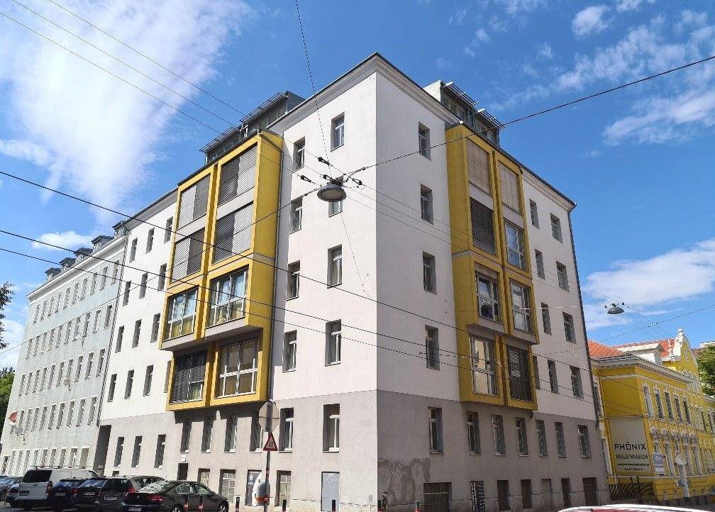 Moderne Gebäudefassade mit markanten gelben Erkern unter blauem Himmel.