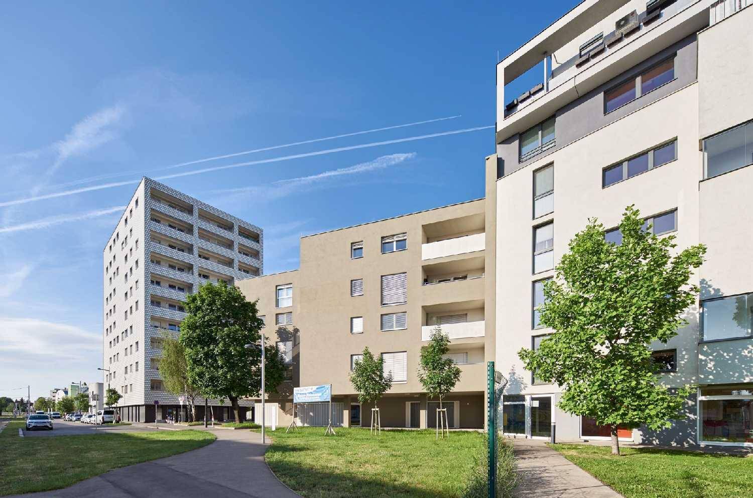 Moderne Wohngebäude mit ansprechender Architektur und gepflegten Grünflächen entlang der Straße.