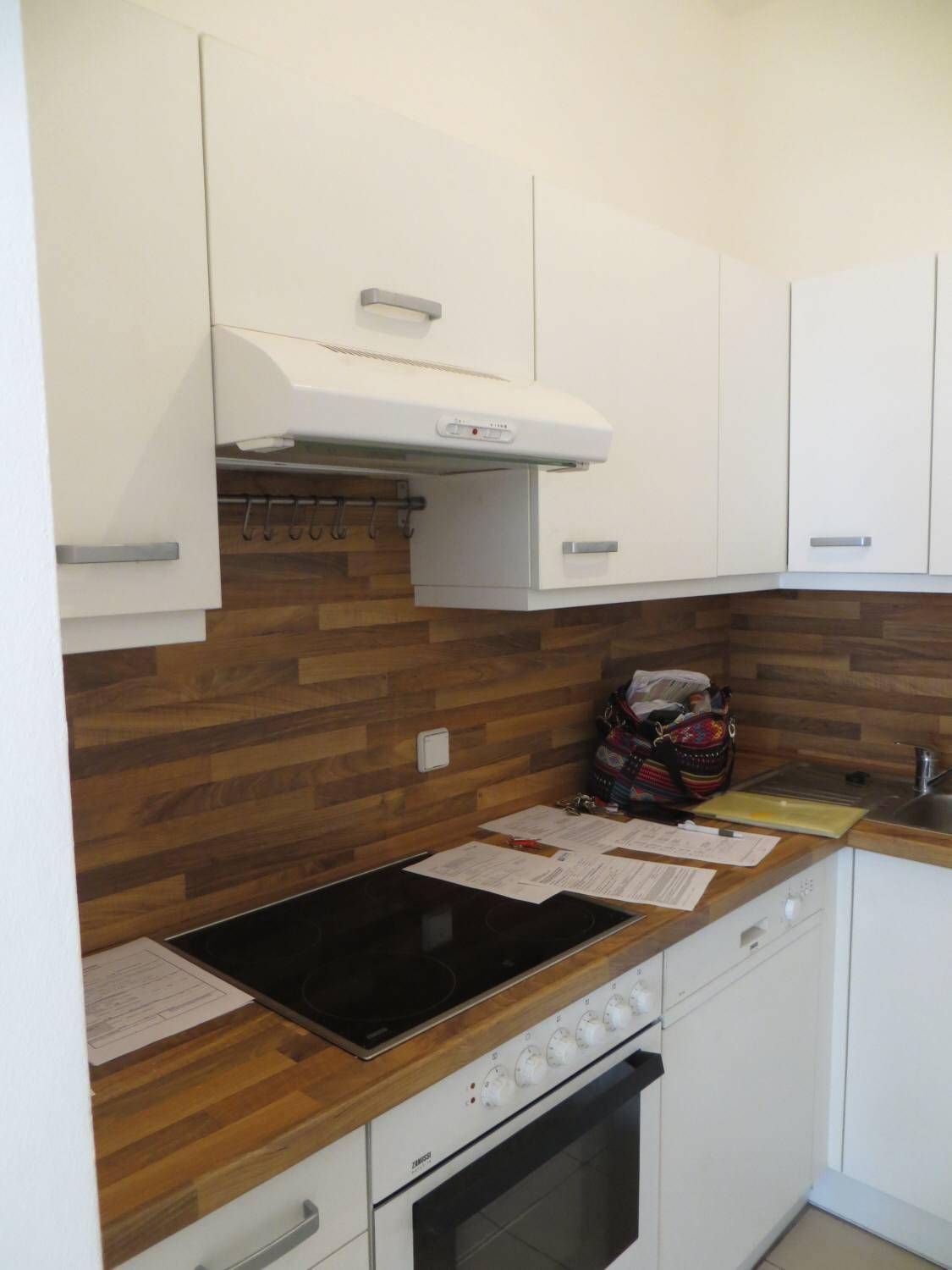 Moderne Einbauküche mit weißen Schränken, Holzoptik-Arbeitsplatte und Induktionskochfeld.