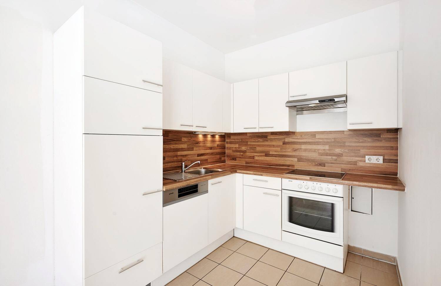 Moderne Einbauküche mit weißen Schränken, Holz-Arbeitsplatte und integrierten Geräten.