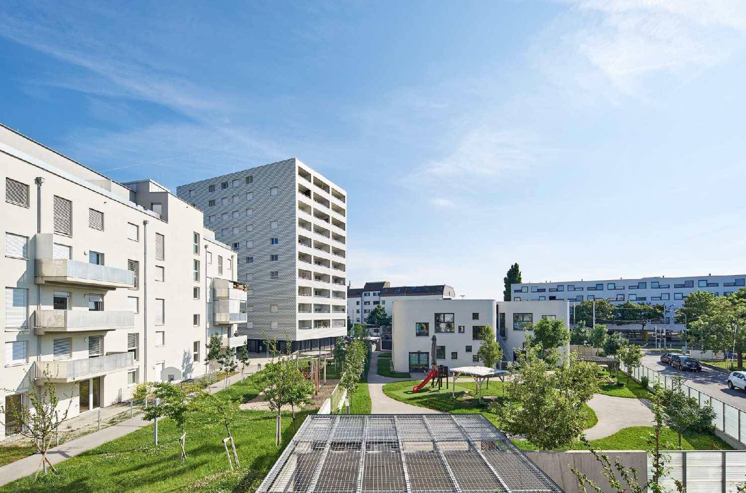 Weitläufige Wohnanlage mit modernen Gebäuden, Grünflächen und Spielplatz.