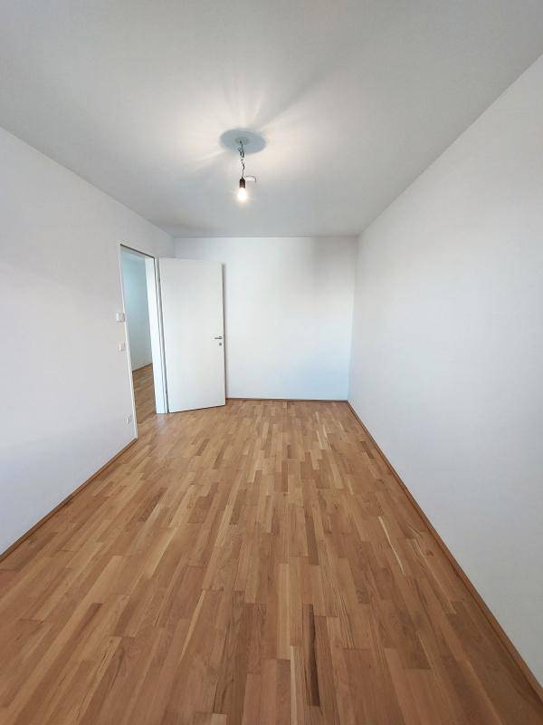 Geräumiges Zimmer mit hellem Parkettboden und weißen Wänden, vielseitig nutzbar als Schlaf- oder Arbeitszimmer.