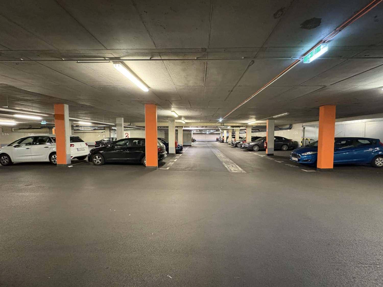 Weitläufige Tiefgarage mit zahlreichen Parkplätzen und guter Beleuchtung.