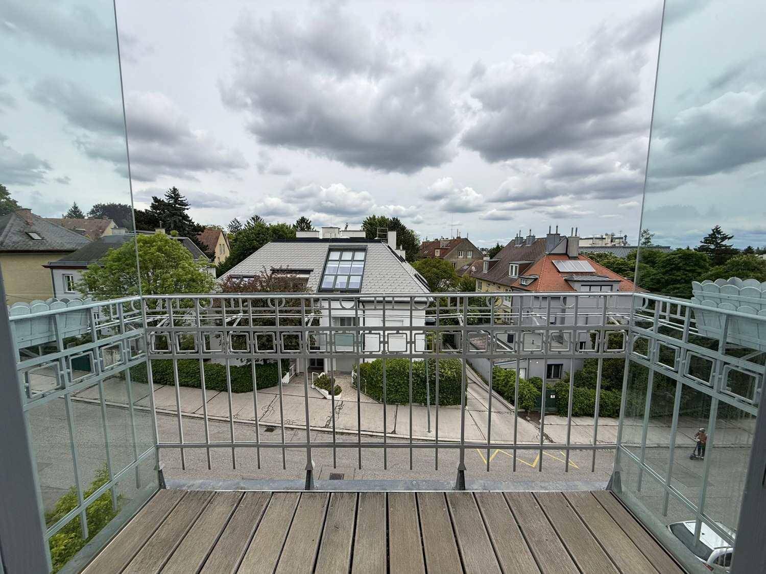 Balkon mit Holzboden und Blick auf die umliegende Wohngegend und Straße.