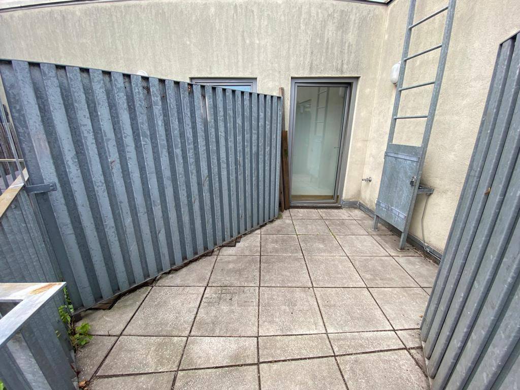 Kleine, geflieste Terrasse mit Metallabtrennungen und Blick auf die Umgebung.
