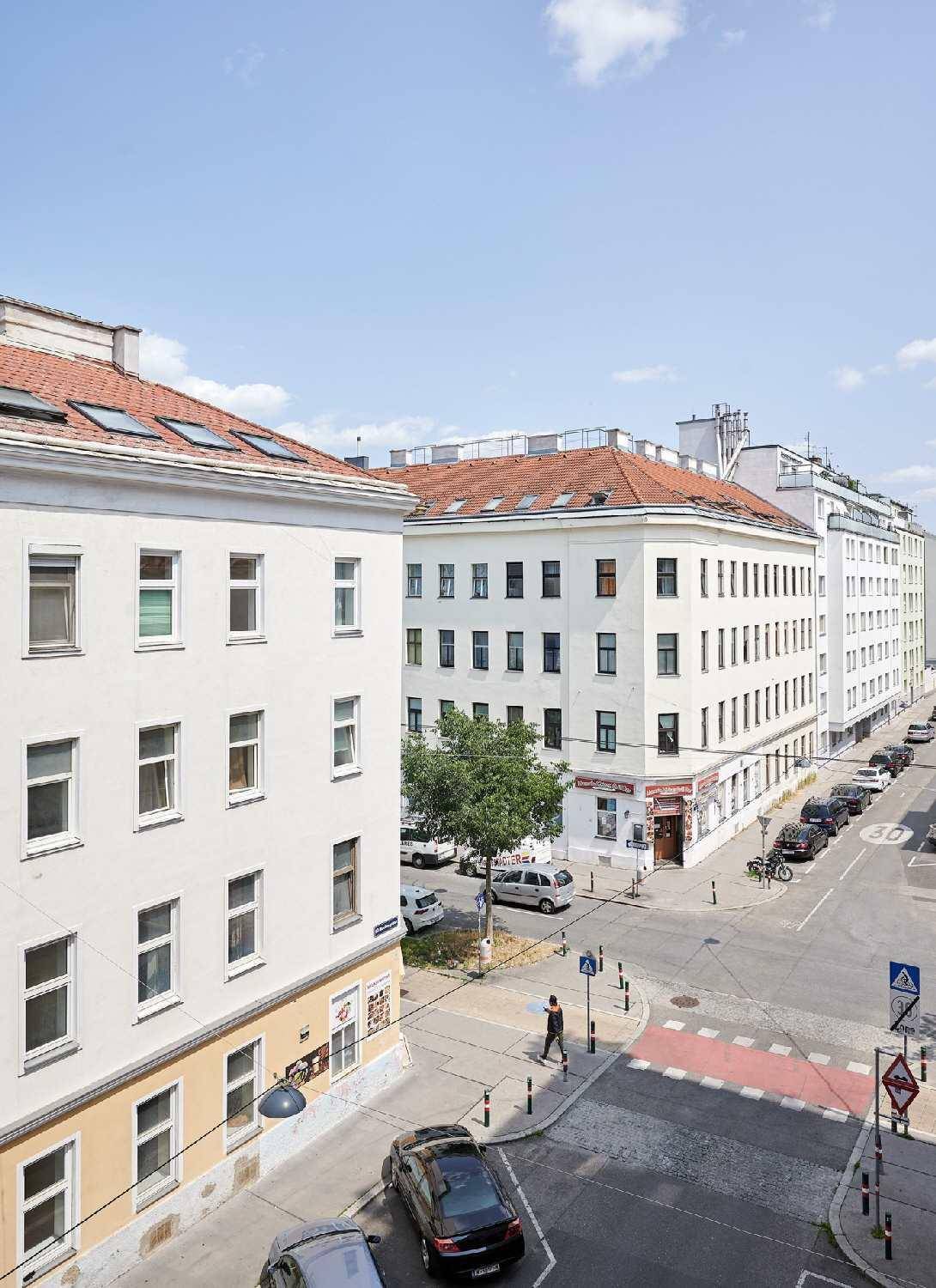 Blick von oben auf eine belebte Stadtkreuzung mit Gebäuden und parkenden Autos.