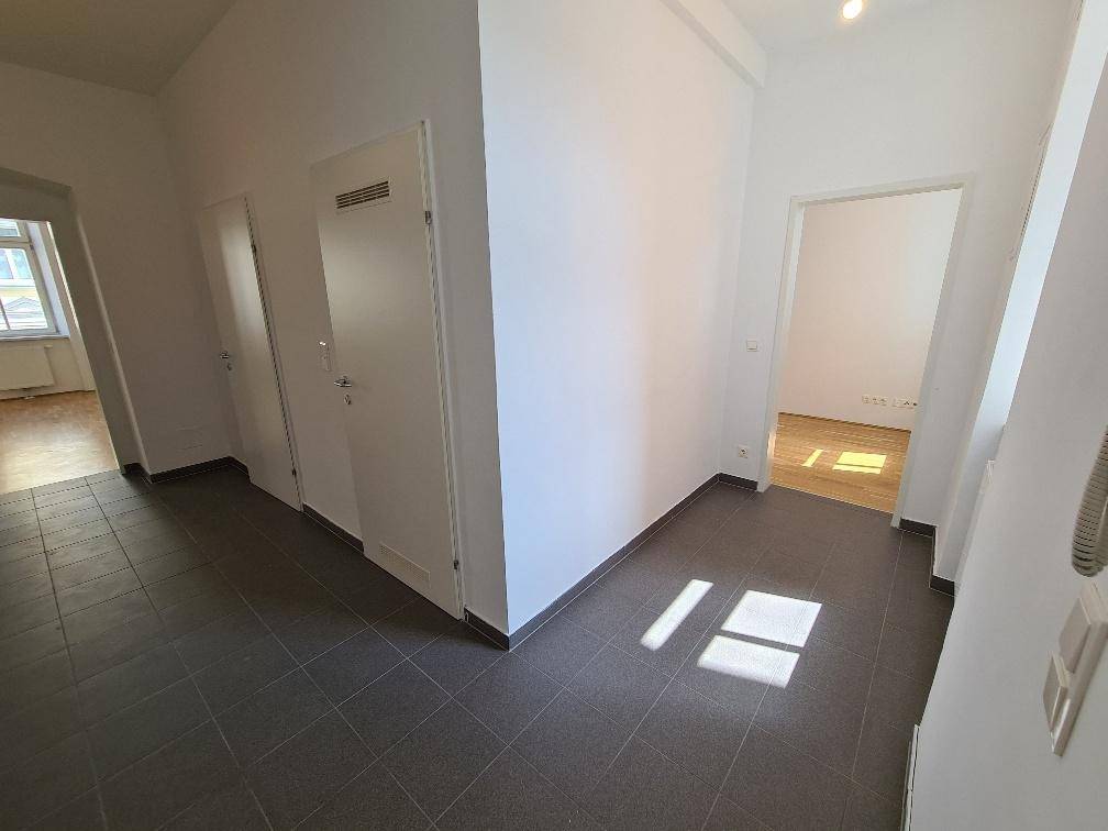 Heller Eingangsbereich mit Fliesenboden und Zugang zu verschiedenen Räumen der Wohnung.