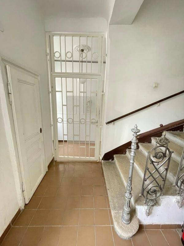 Eingangsbereich mit Steintreppe, schmiedeeisernem Geländer und gefliestem Boden.