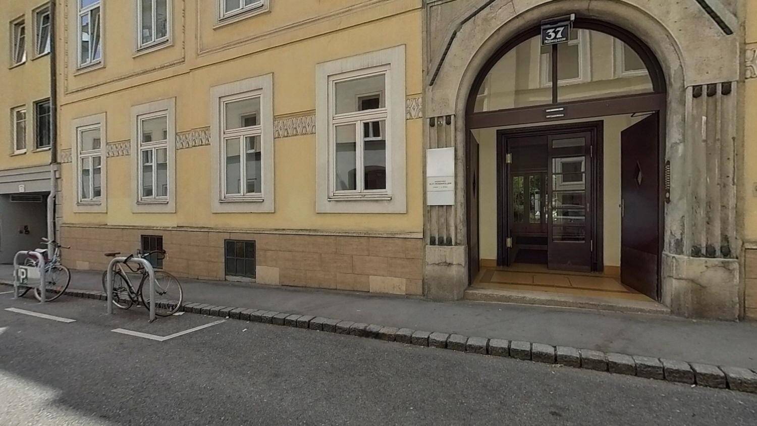 Eingangsbereich eines historischen Gebäudes mit Hausnummer 37 und Fahrrädern davor.