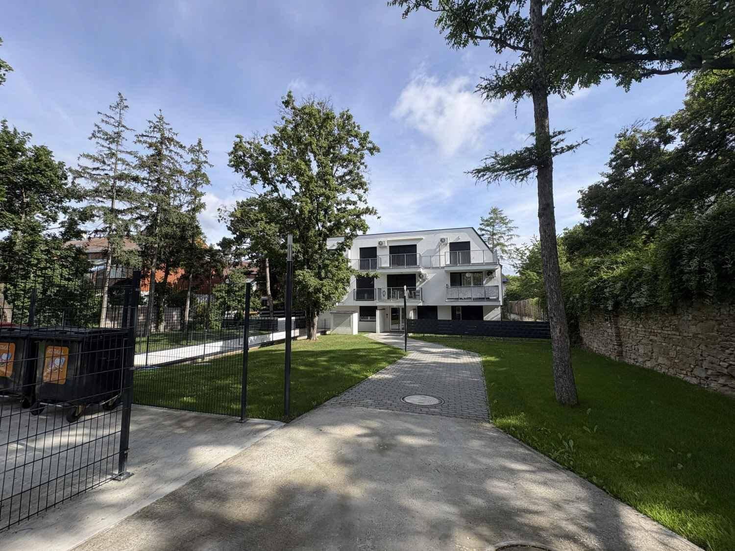 Moderne Wohnanlage mit weißer Fassade, Balkonen und umgebender Grünfläche.