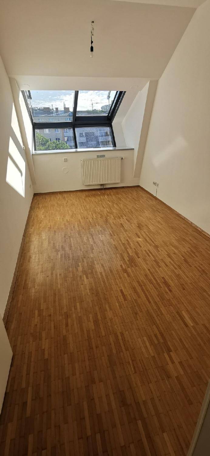 Lichtdurchflutetes Zimmer mit Holzparkett und großem Dachfenster, ideal für Schlaf- oder Arbeitszwecke.