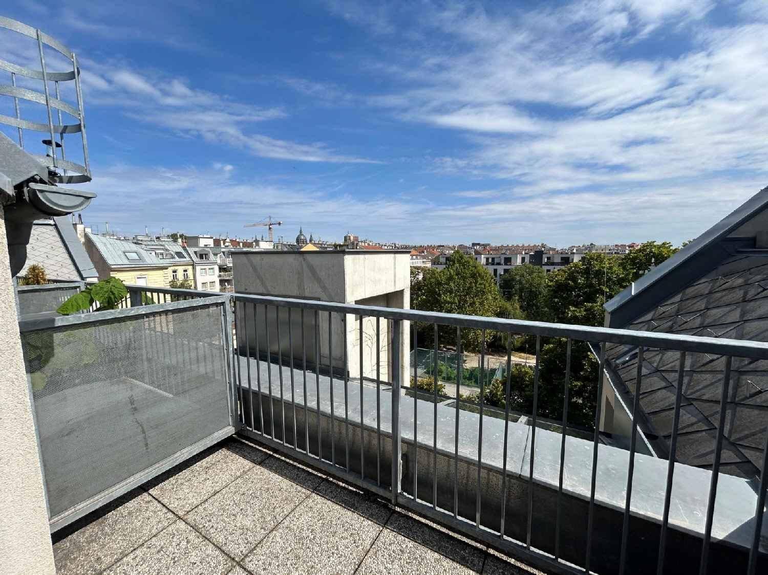 Geräumiger Balkon mit Weitblick über die Stadt und die umliegenden Dächer unter blauem Himmel.