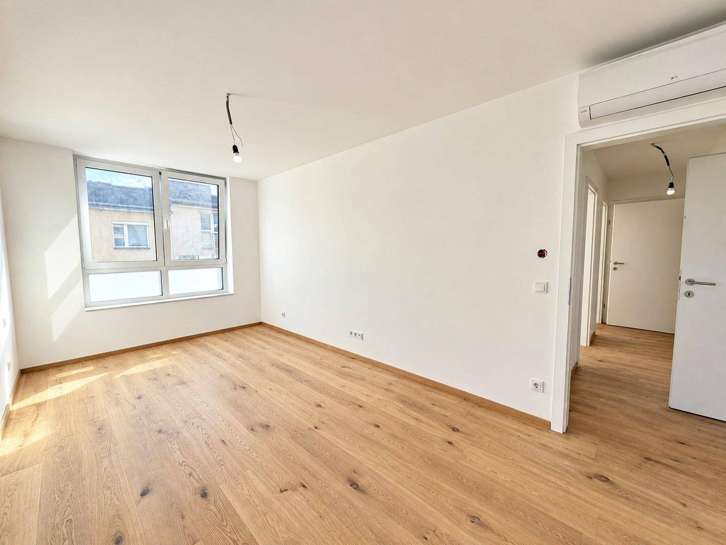 Helles Schlafzimmer mit Eichenparkett, Klimaanlage und Blick ins Grüne.