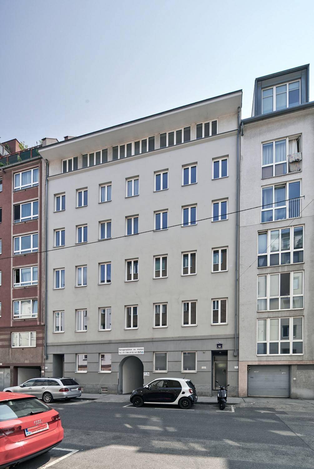 Mehrstöckiges Wohngebäude mit heller Fassade und vielen Fenstern an einem sonnigen Tag.