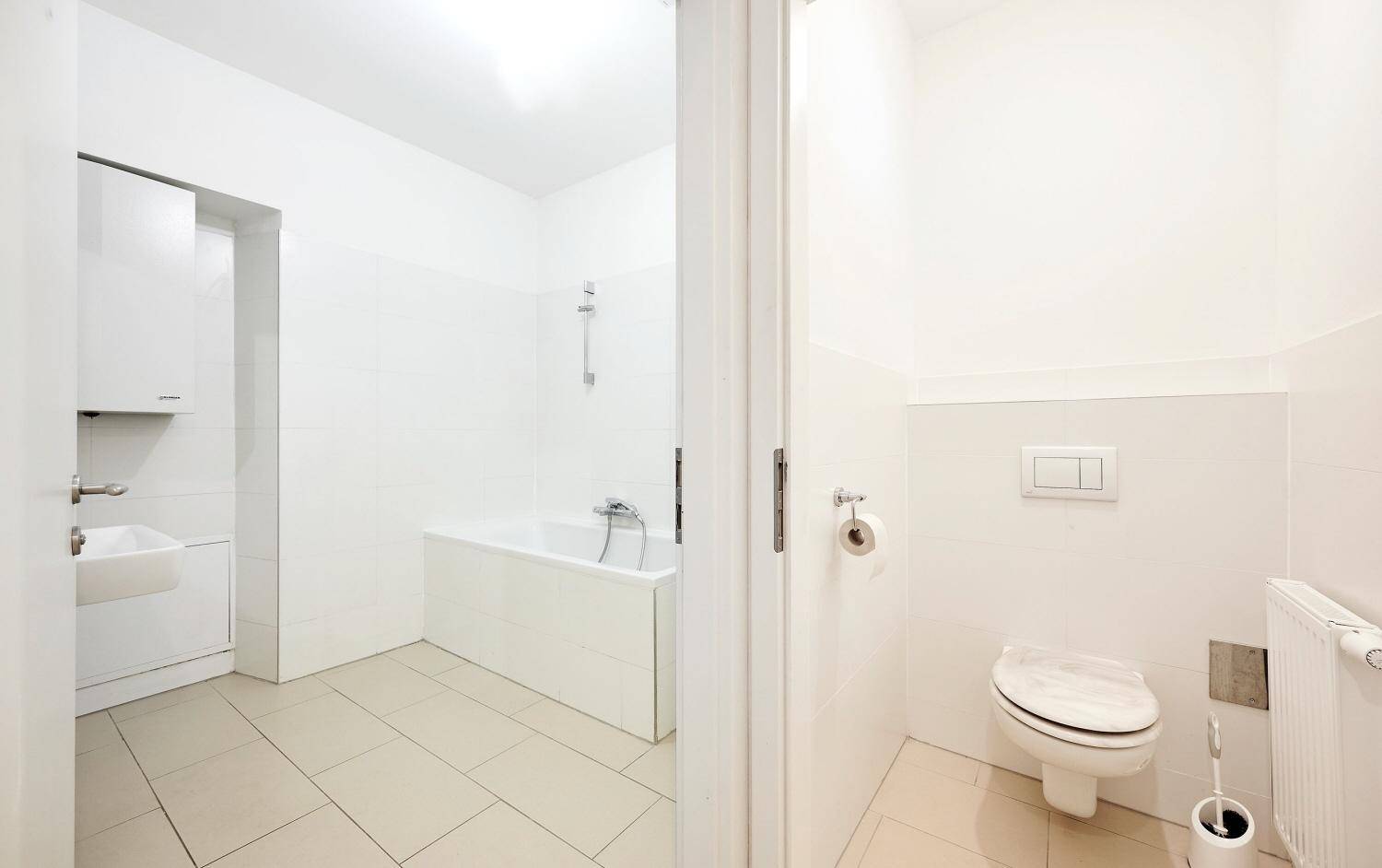 Blick vom Flur in ein Badezimmer mit Badewanne und ein separates WC.