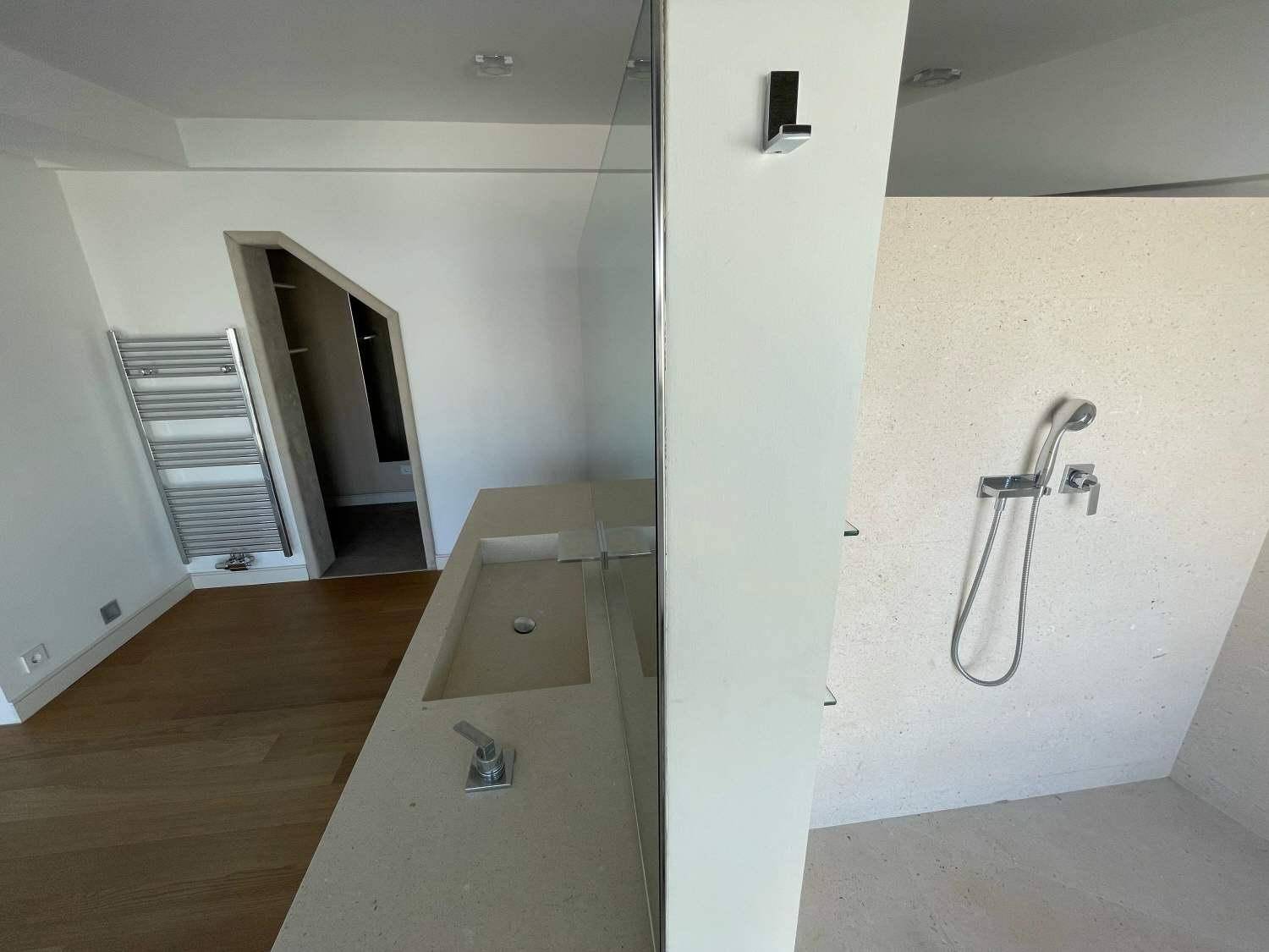Helles Badezimmer mit begehbarer Dusche, Einzelwaschbecken und beheiztem Handtuchhalter unter Dachschrägen.