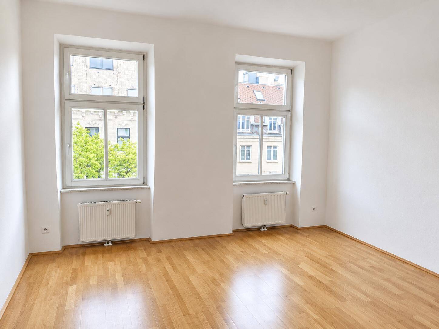 Geräumiges, helles Zimmer mit Parkettboden und zwei großen Fenstern, ideal als Schlafzimmer.