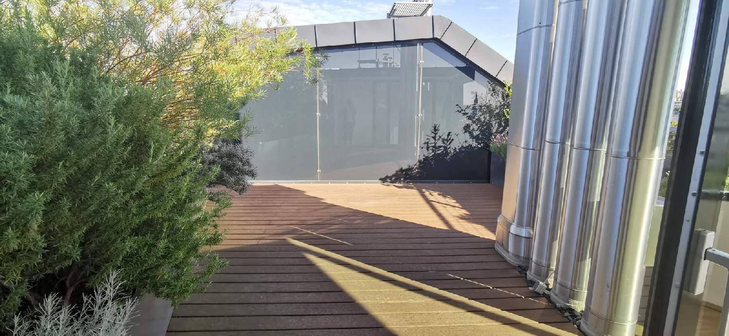 Moderne Dachterrasse mit Holzbelag und üppiger Bepflanzung, bietet einen privaten Außenbereich.