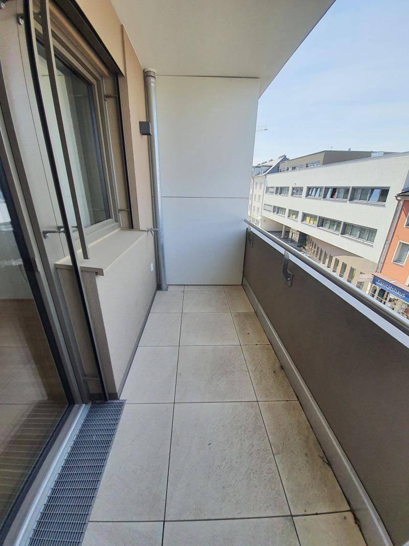 Schmaler Balkon mit Fliesenboden und Blick auf die umliegende Stadtbebauung.