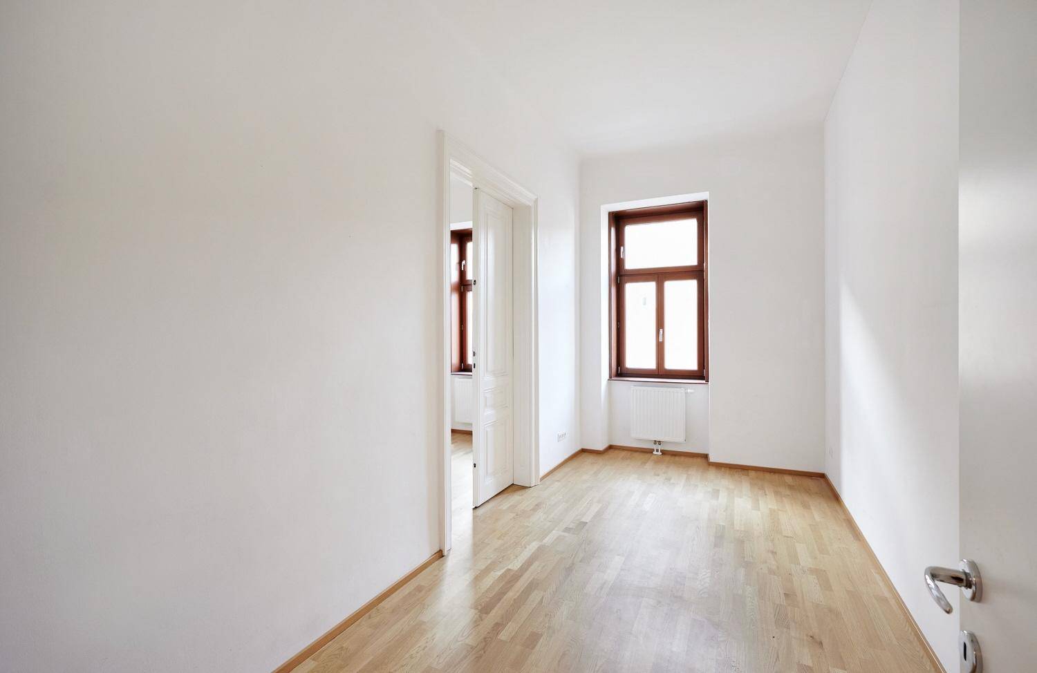 Heller Flur mit Parkettboden und Zugang zu einem weiteren Zimmer.