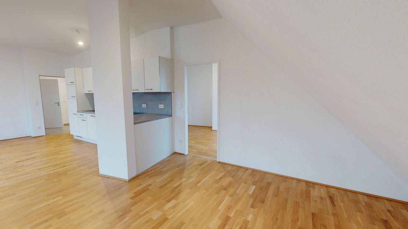 Geräumiger Wohnbereich mit Holzboden und Zugang zur modernen Küchenzeile.