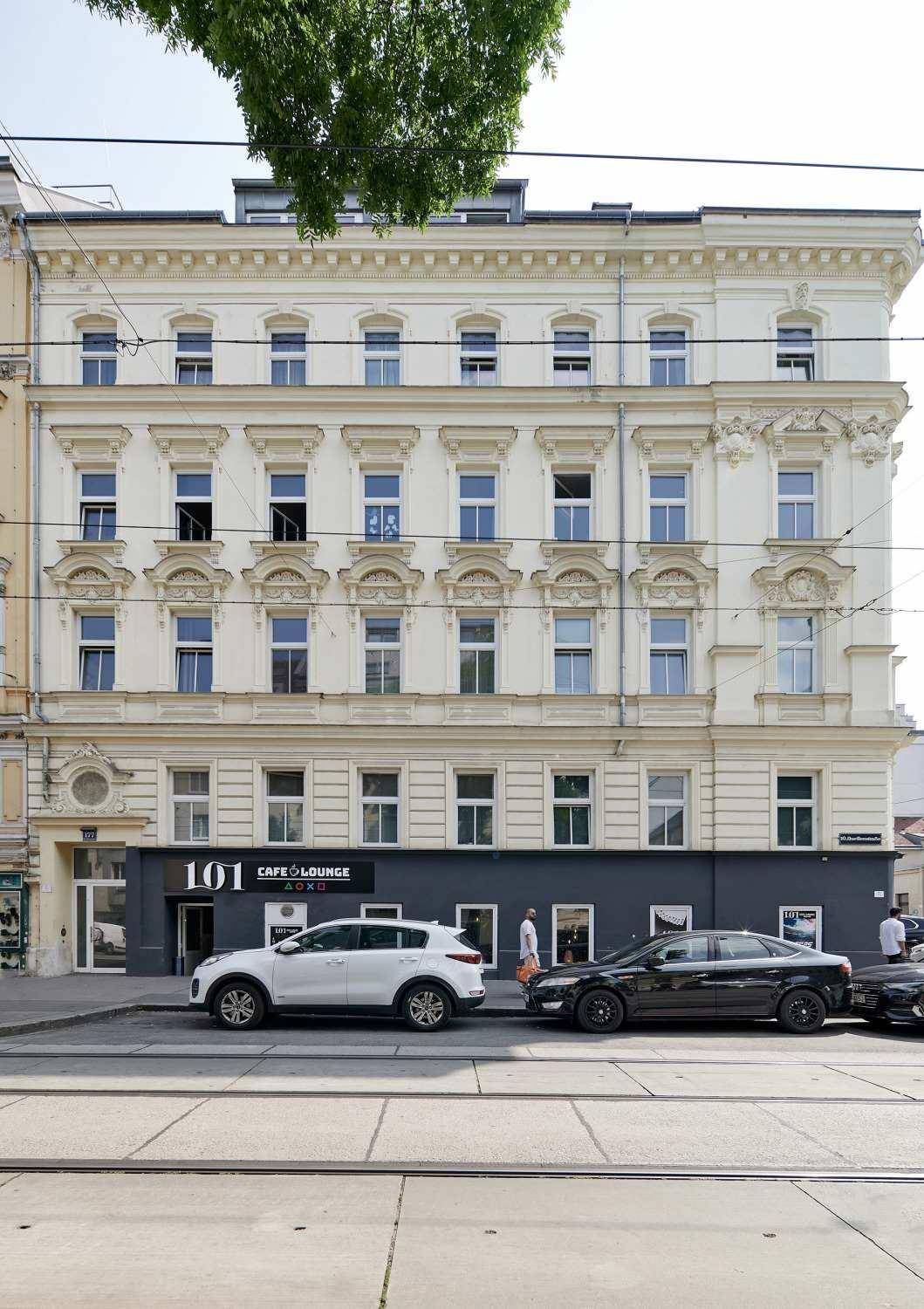 Klassische Fassade eines Altbaus mit vielen Fenstern und einem Geschäft im Erdgeschoss.