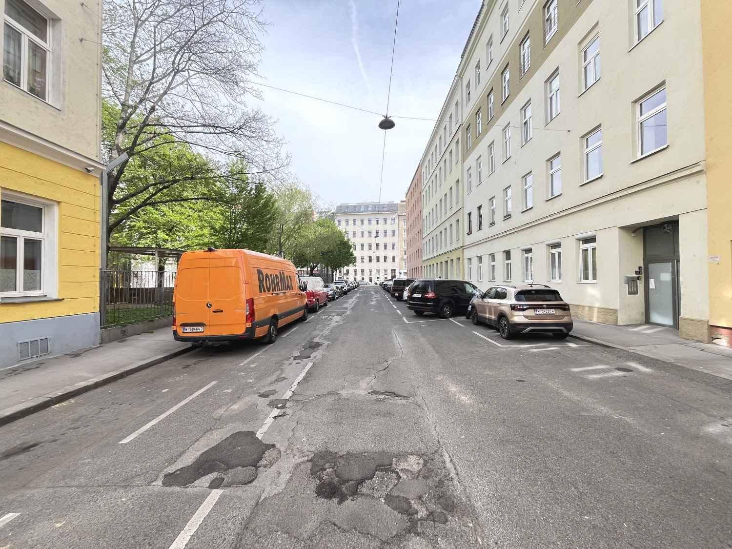 Eine ruhige Wohnstraße mit parkenden Autos und Bäumen entlang der Gebäude im Frühling.