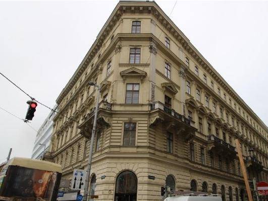 Eindrucksvolles Eckgebäude mit historischer Architektur, vielen Fenstern und dekorativen Balkonen.