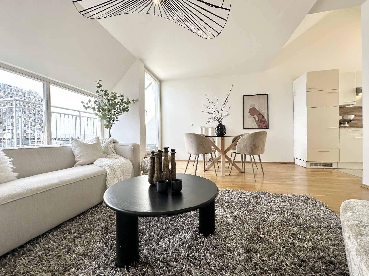 Geräumiger Wohn-Essbereich mit beigem Sofa, Esstisch und offenem Zugang zur Küche.