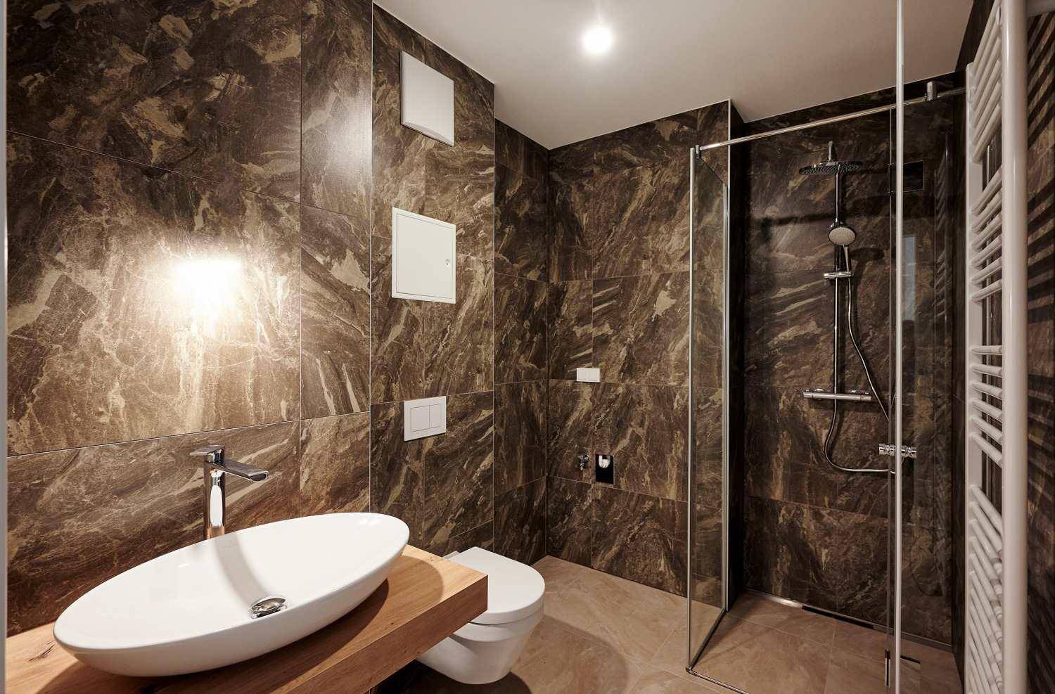 Modernes Badezimmer mit dunklen Marmorfliesen, begehbarer Dusche und Einzelwaschbecken.