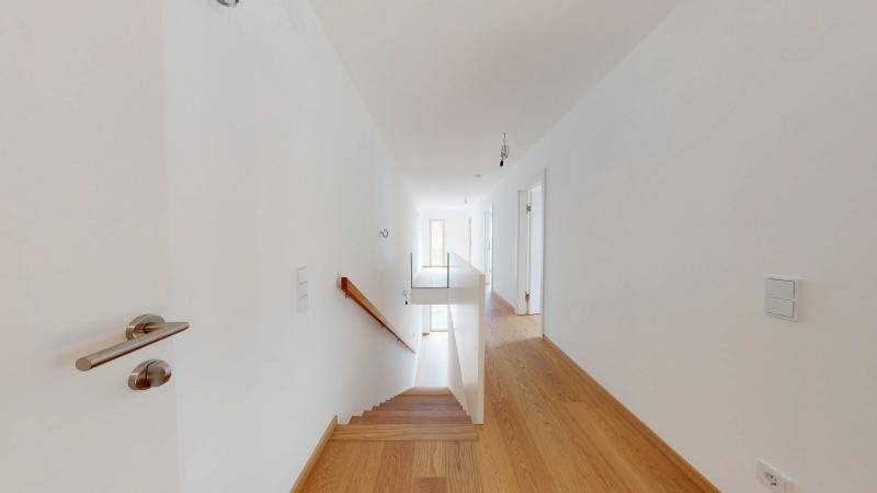 Heller Flur mit Eichenparkettboden und einer modernen Treppe zu den oberen Etagen.