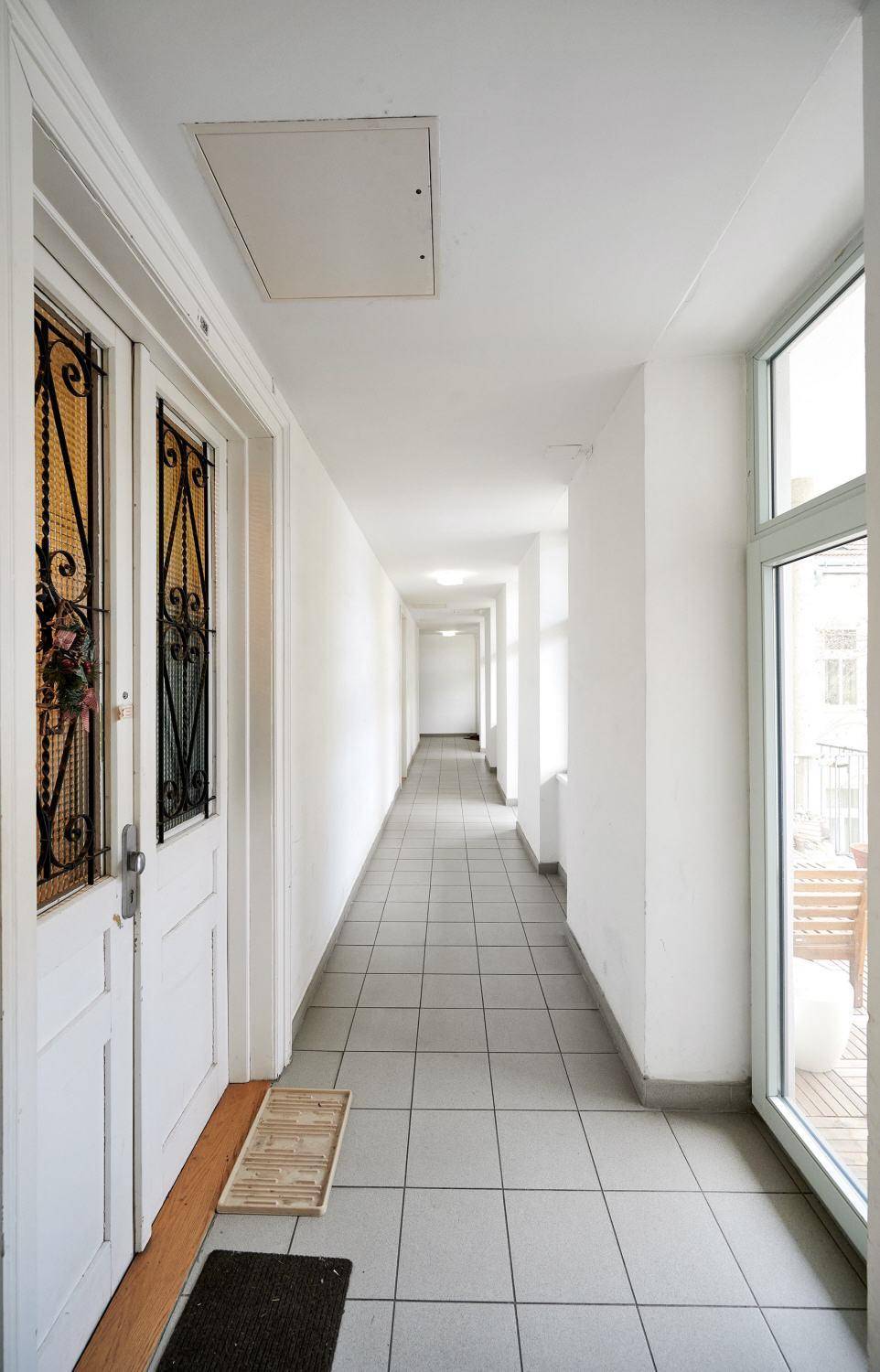 Langer, heller Flur mit Fliesenboden und Zugang zu einem Balkon oder einer Terrasse.