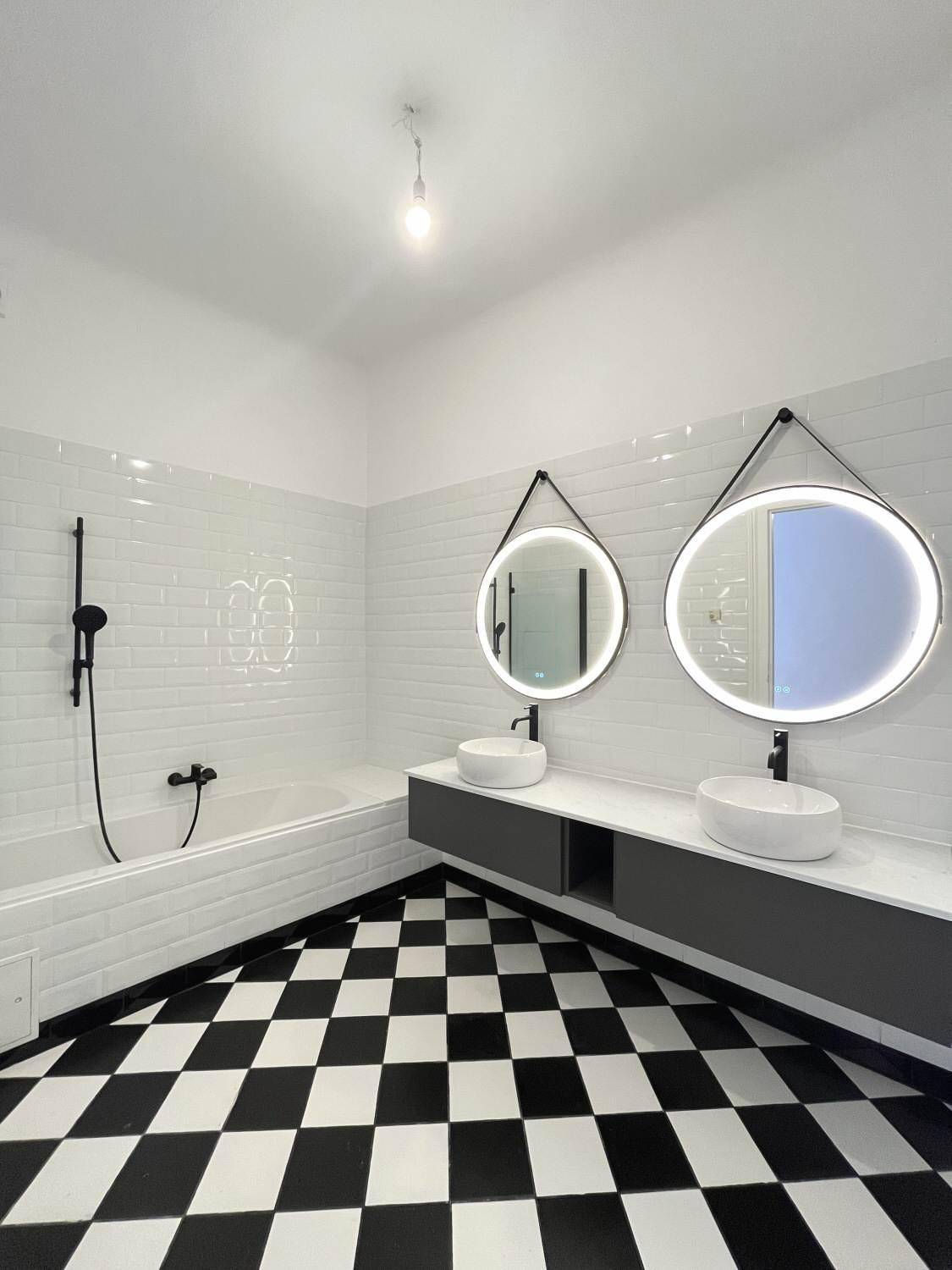 Modernes Badezimmer mit schwarz-weißem Schachbrettmuster-Fliesenboden und Doppelwaschbecken.