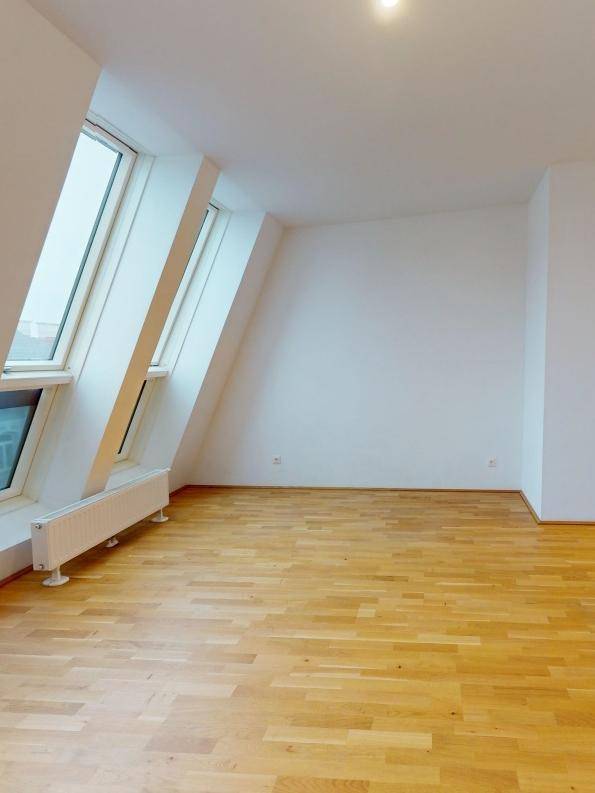 Geräumiger Dachgeschossraum mit Holzboden und schrägen Wänden, ideal für individuelle Gestaltung.