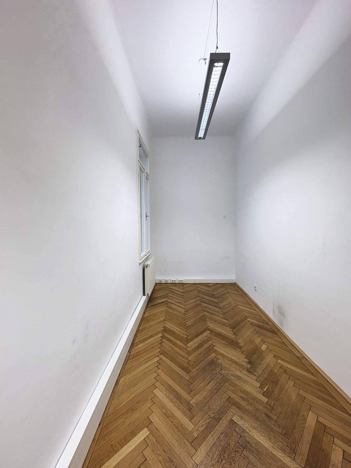 Schmaler Raum mit Fischgrätparkett und einem Fenster, ideal als kleines Büro oder Abstellraum.